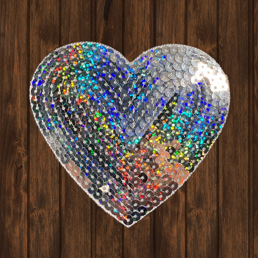 Heart-shaped patch with sparkling silver sequins creating a dazzling rainbow effect. Ideal for adding shine to clothing, bags, or DIY craft projects